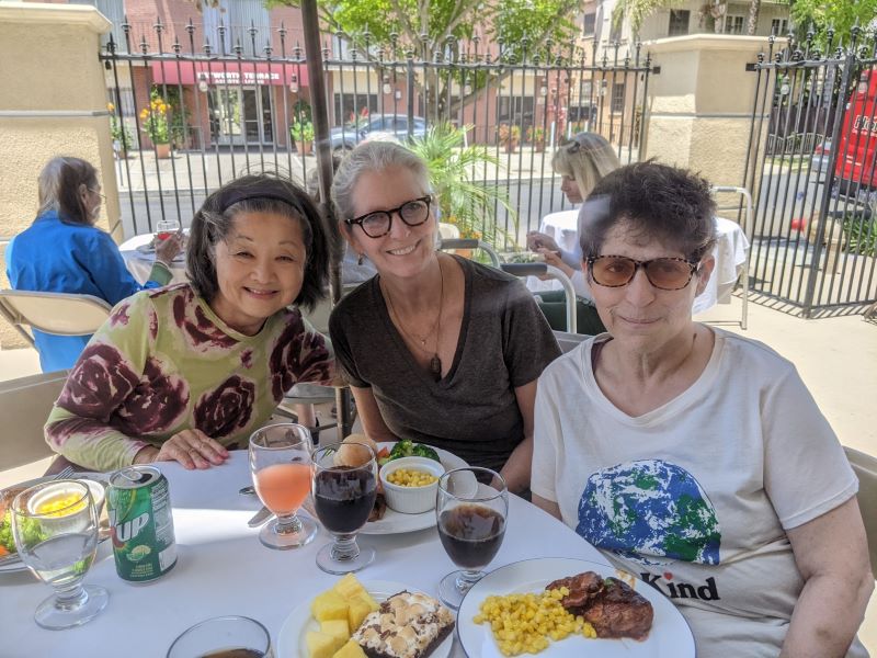 Portrait shot of memory care giver and seniors eating lunch on a patio